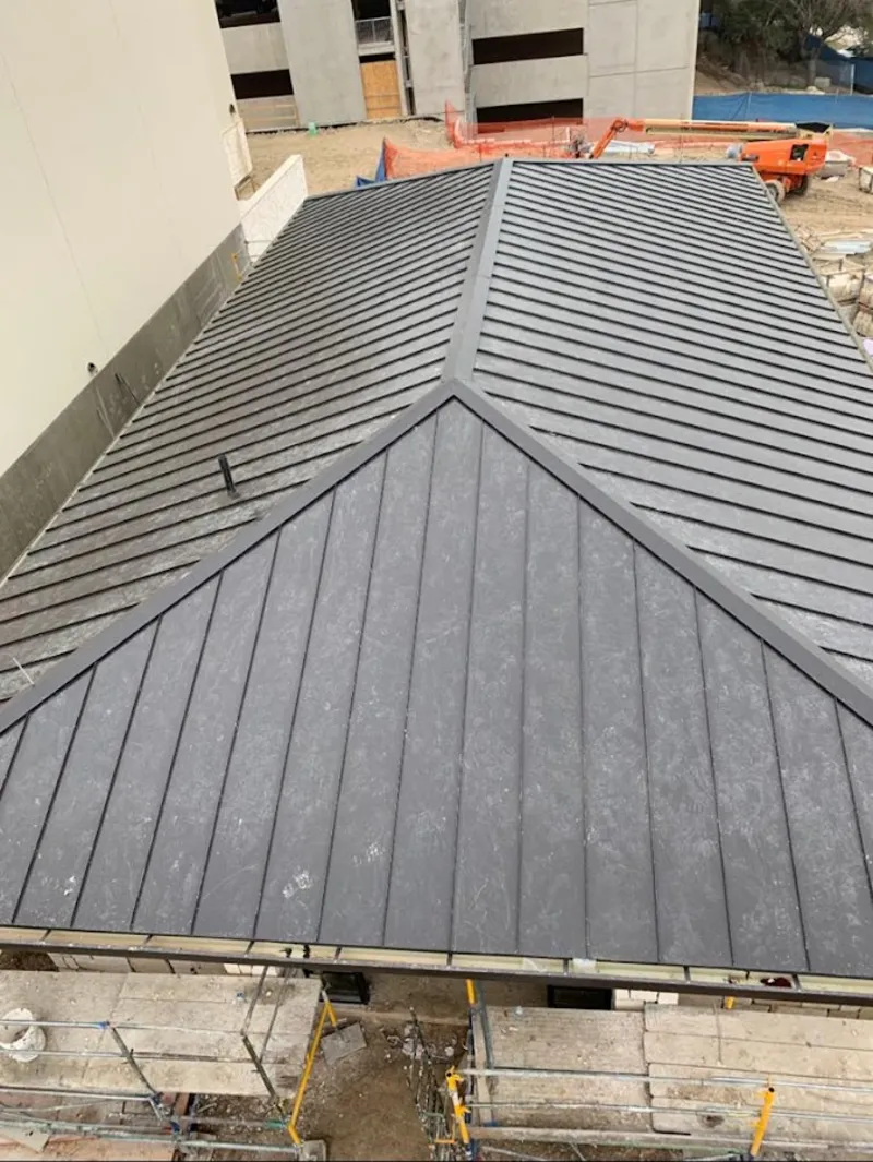 Commercial metal roof construction with crane equipment in Manchester